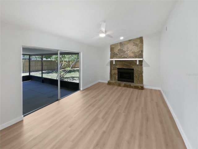 unfurnished living room featuring baseboards, ceiling fan, a fireplace, and wood finished floors