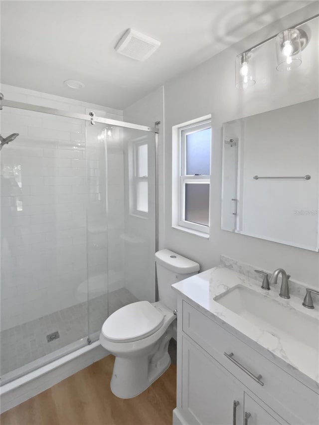 bathroom featuring visible vents, a stall shower, wood finished floors, vanity, and toilet