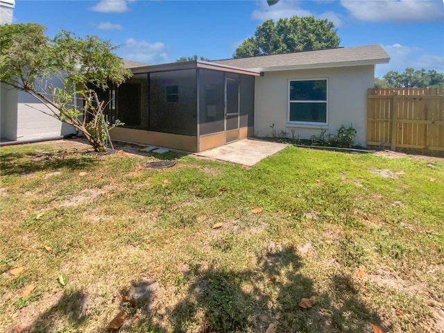 rear view of property with fence, a lawn, stucco siding, and a sunroom