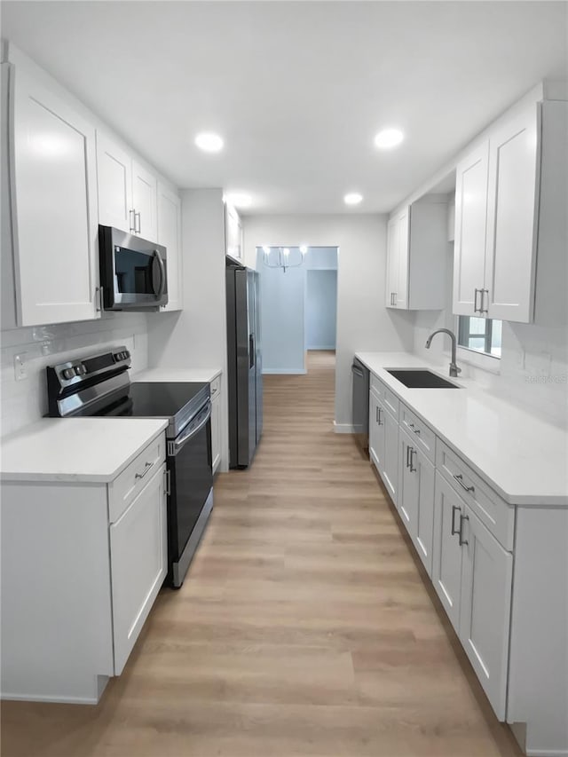 kitchen featuring light wood-style floors, a sink, appliances with stainless steel finishes, and recessed lighting