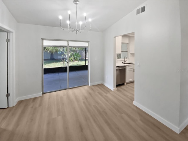 unfurnished dining area with a sink, light wood finished floors, a chandelier, baseboards, and visible vents