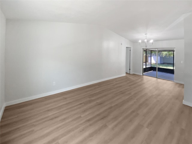 unfurnished room with baseboards, an inviting chandelier, light wood finished floors, and vaulted ceiling