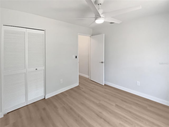 unfurnished bedroom featuring baseboards, a ceiling fan, a closet, and light wood-type flooring