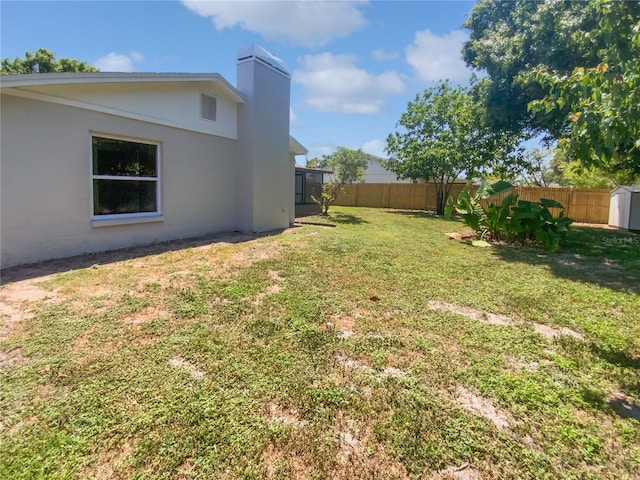 view of yard featuring a storage shed, an outdoor structure, and a fenced backyard