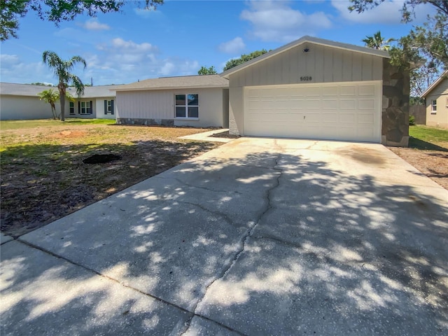 ranch-style house featuring concrete driveway, an attached garage, and a front yard