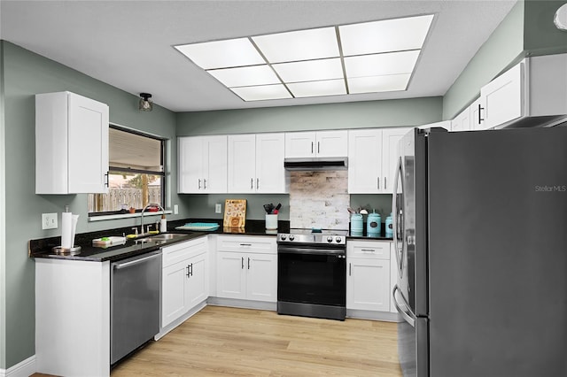 kitchen featuring under cabinet range hood, white cabinets, appliances with stainless steel finishes, and a sink