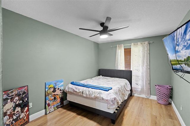 bedroom with baseboards, a textured ceiling, ceiling fan, and wood finished floors