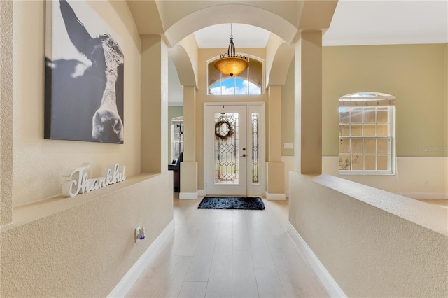 foyer with arched walkways and baseboards