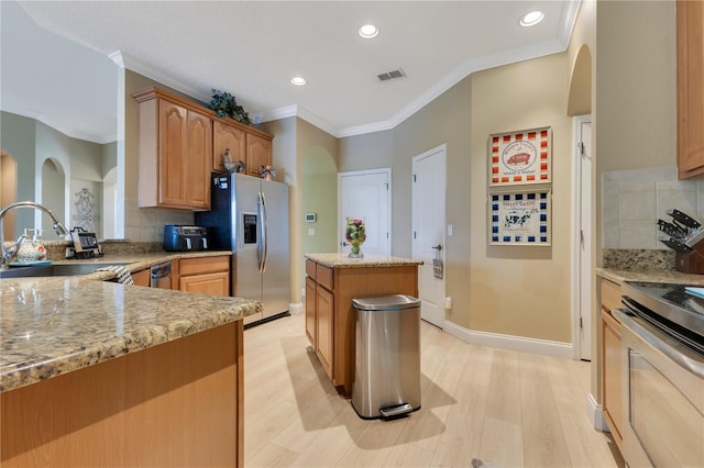 kitchen with a sink, ornamental molding, backsplash, and stainless steel appliances