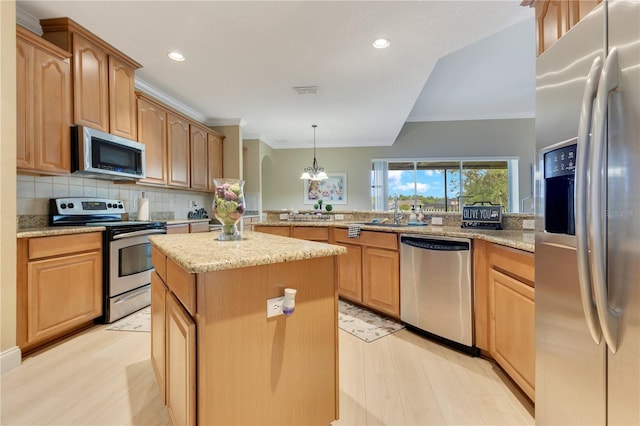 kitchen featuring backsplash, crown molding, a center island, stainless steel appliances, and light wood-style flooring