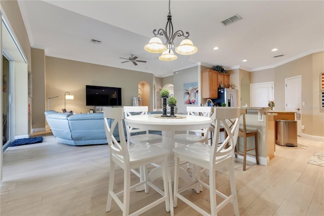 dining room with arched walkways, a ceiling fan, visible vents, and light wood-type flooring