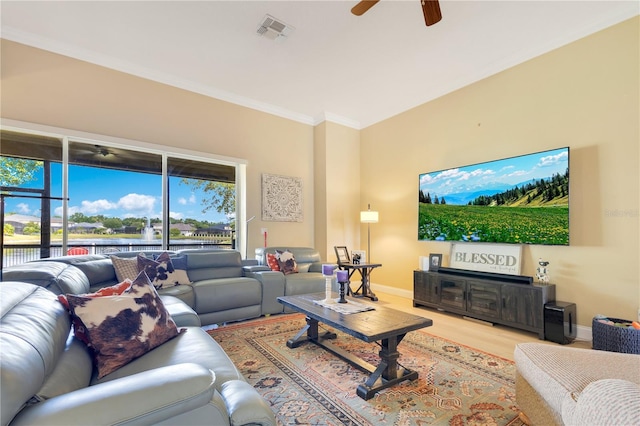 living area featuring a ceiling fan, visible vents, wood finished floors, baseboards, and ornamental molding