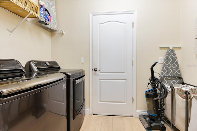 clothes washing area featuring baseboards, laundry area, light wood-style flooring, and washer and dryer