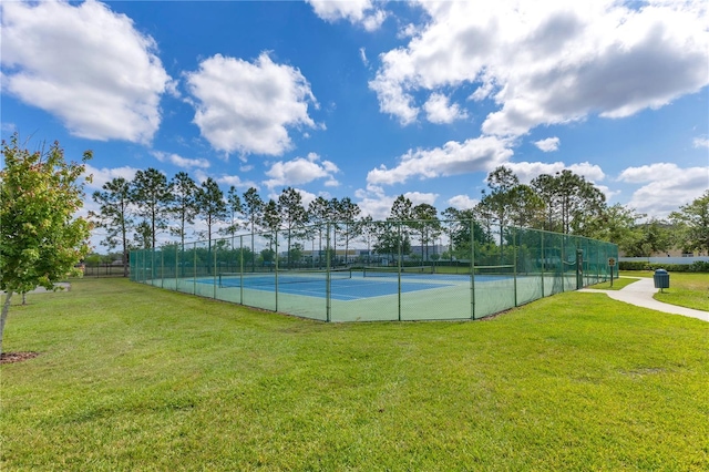 view of tennis court with fence and a lawn