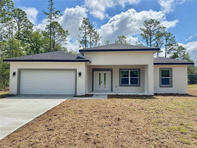 prairie-style house featuring a garage, stucco siding, concrete driveway, and french doors