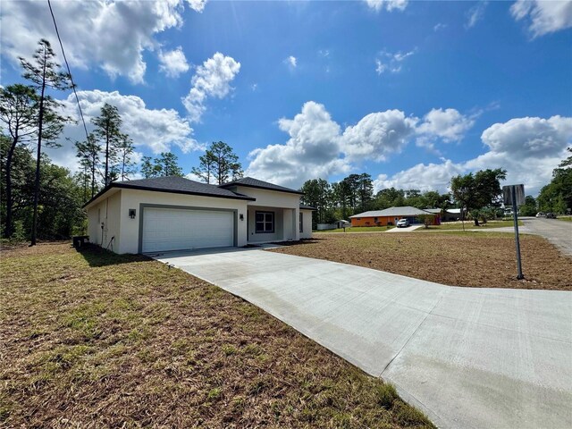 view of front of home featuring a garage, stucco siding, driveway, and a front lawn