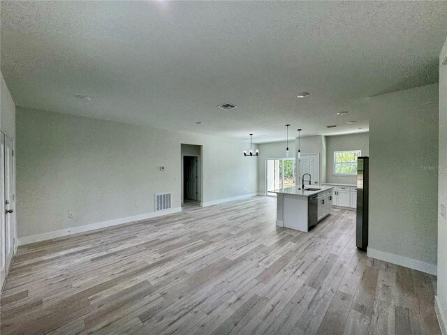kitchen with visible vents, a sink, freestanding refrigerator, open floor plan, and light wood-style flooring
