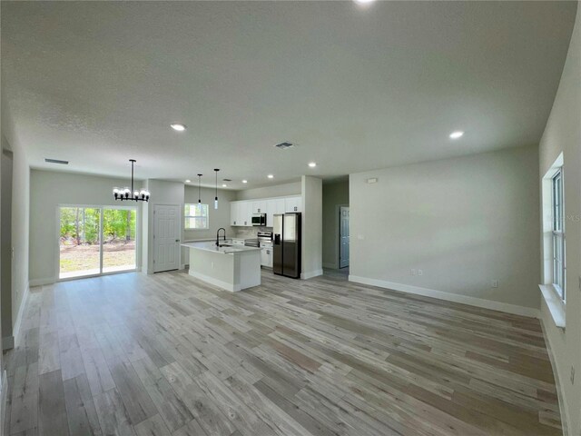 kitchen featuring an inviting chandelier, open floor plan, recessed lighting, a sink, and stainless steel appliances