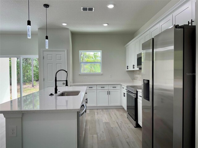 kitchen with visible vents, light wood-style floors, white cabinetry, a sink, and appliances with stainless steel finishes