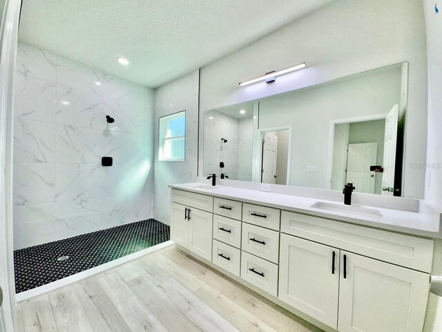 bathroom with a sink, a marble finish shower, and wood finished floors