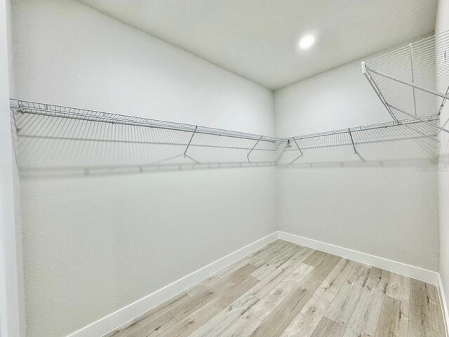walk in closet with light wood finished floors