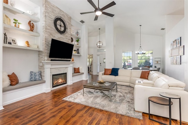 living area with ceiling fan, a high end fireplace, built in features, wood finished floors, and high vaulted ceiling