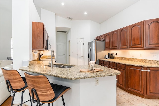 kitchen with stainless steel appliances, light stone counters, a sink, and a peninsula