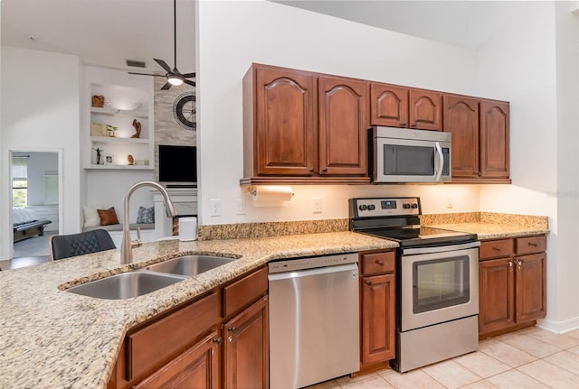 kitchen with light stone counters, a sink, appliances with stainless steel finishes, and ceiling fan