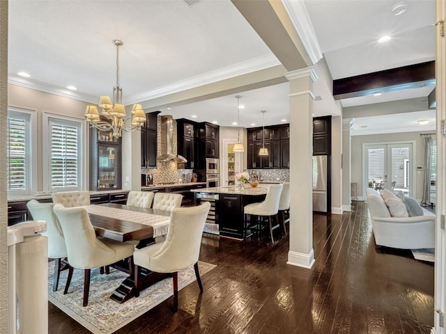 dining area featuring an inviting chandelier, crown molding, decorative columns, dark wood-type flooring, and recessed lighting