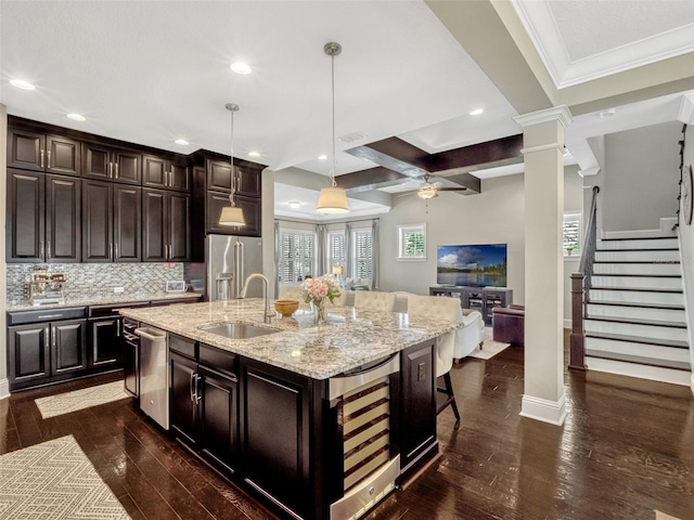 kitchen with ceiling fan, a sink, dark wood finished floors, an island with sink, and stainless steel appliances