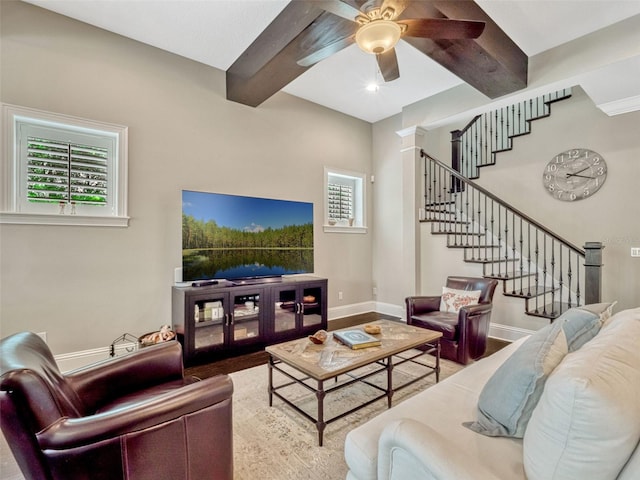 living room with ceiling fan, beamed ceiling, stairs, and wood finished floors
