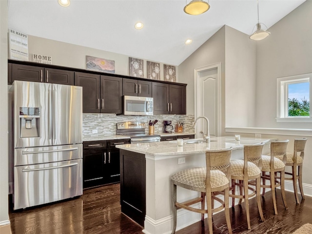 kitchen with dark wood-style flooring, tasteful backsplash, a sink, a breakfast bar, and stainless steel appliances