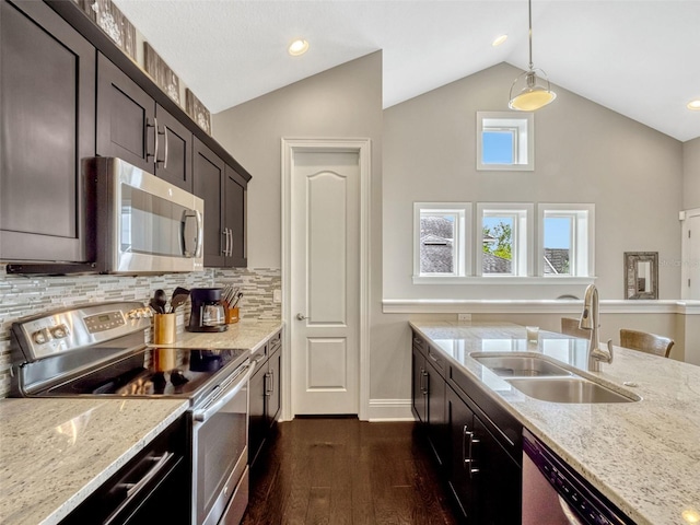 kitchen with appliances with stainless steel finishes, light stone countertops, a sink, baseboards, and dark wood-type flooring