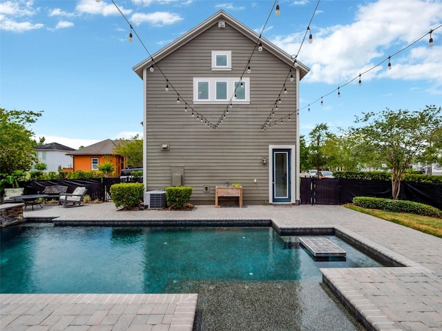 rear view of house with a fenced in pool, fence, central AC unit, and a patio area