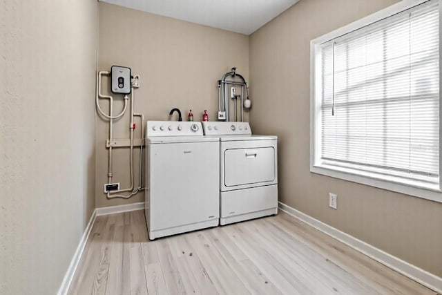 5004 E Seneca Ave, Tampa, FL 33617 - laundry area featuring washer and clothes dryer, light wood finished floors, baseboards, and plenty of natural light