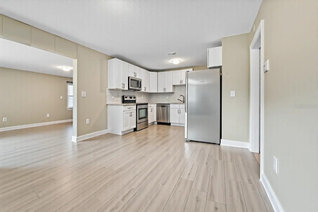 5004 E Seneca Ave, Tampa, FL 33617 - kitchen featuring appliances with stainless steel finishes, light wood finished floors, light countertops, baseboards, and a sink