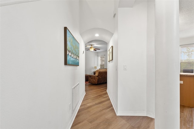 hallway featuring light wood-type flooring, a healthy amount of sunlight, and visible vents