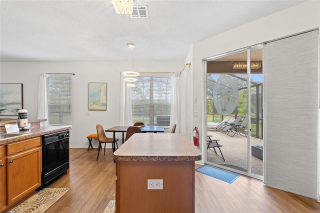 kitchen with a center island, black dishwasher, light wood finished floors, an inviting chandelier, and visible vents