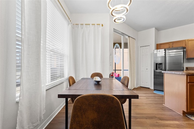 dining space featuring an inviting chandelier, a wealth of natural light, and light wood-style flooring