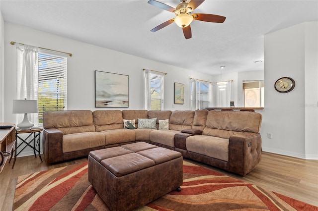 living area featuring a ceiling fan, baseboards, and wood finished floors