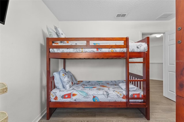 bedroom featuring visible vents, wood finished floors, and baseboards