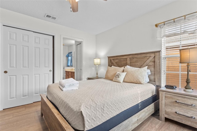 bedroom with connected bathroom, wood finished floors, a closet, visible vents, and ceiling fan