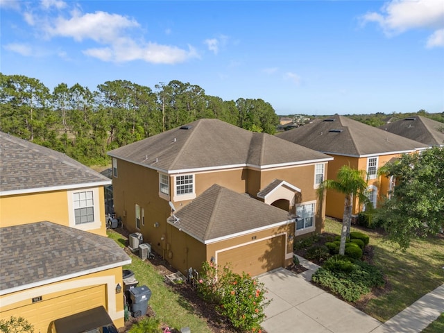 view of side of property with central AC, driveway, stucco siding, and an attached garage