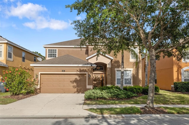 traditional-style home featuring concrete driveway, a garage, and stucco siding