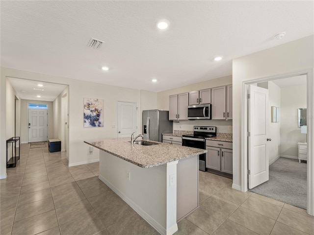 kitchen featuring a sink, an island with sink, gray cabinetry, and stainless steel appliances