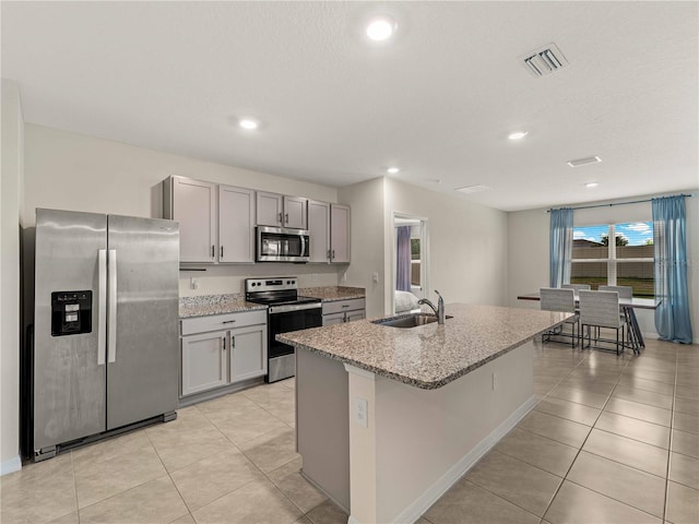 kitchen featuring gray cabinets, visible vents, appliances with stainless steel finishes, a sink, and light tile patterned floors
