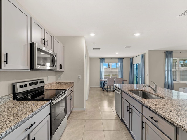 kitchen with light stone countertops, a sink, stainless steel appliances, baseboards, and visible vents