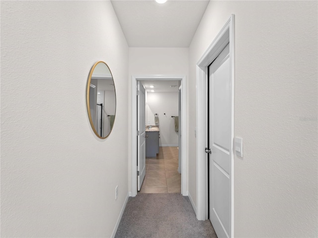 hallway featuring baseboards and carpet flooring