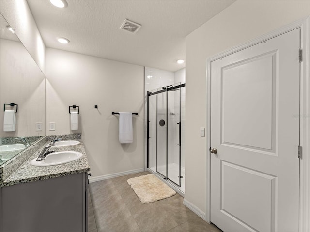 bathroom with a sink, double vanity, baseboards, visible vents, and a stall shower