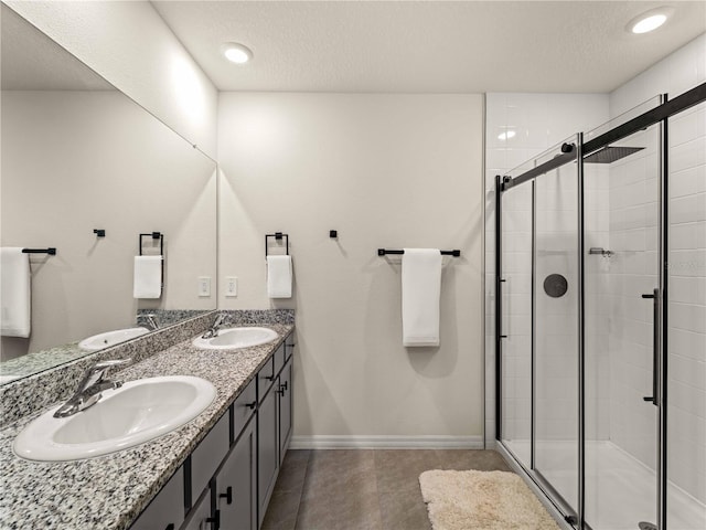 full bath with baseboards, a sink, a textured ceiling, and a shower stall